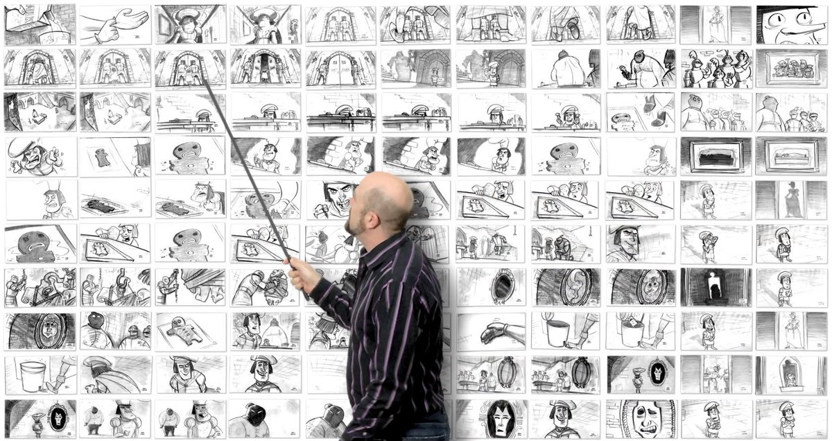 man holding a pointer pointing at a drawing in front of a storyboard wall